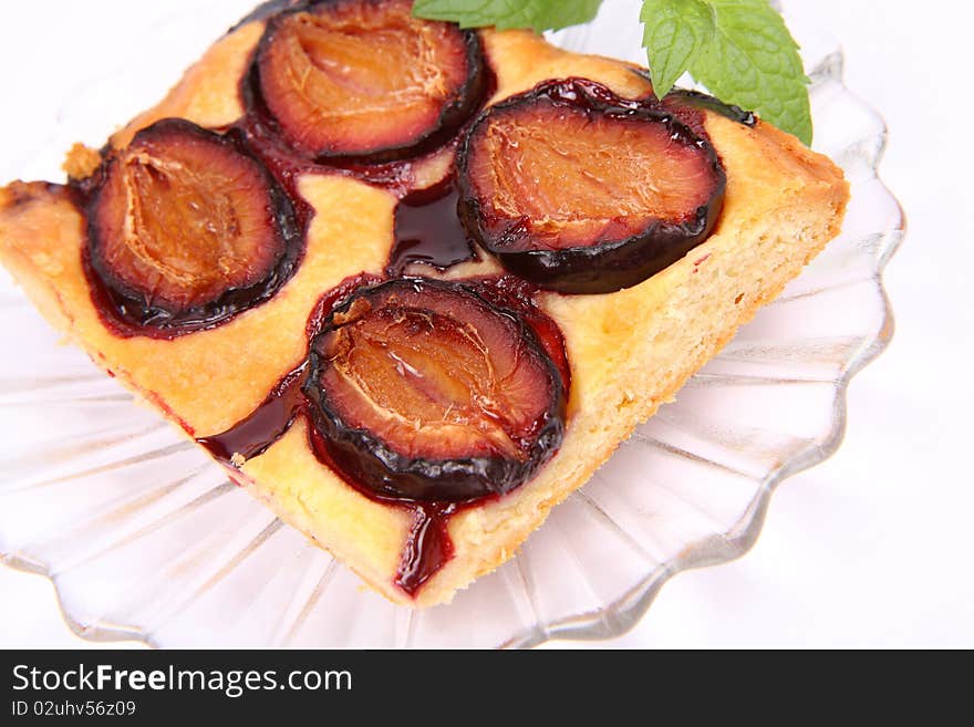 Piece of Plum Pie on a plate decorated with a mint twig