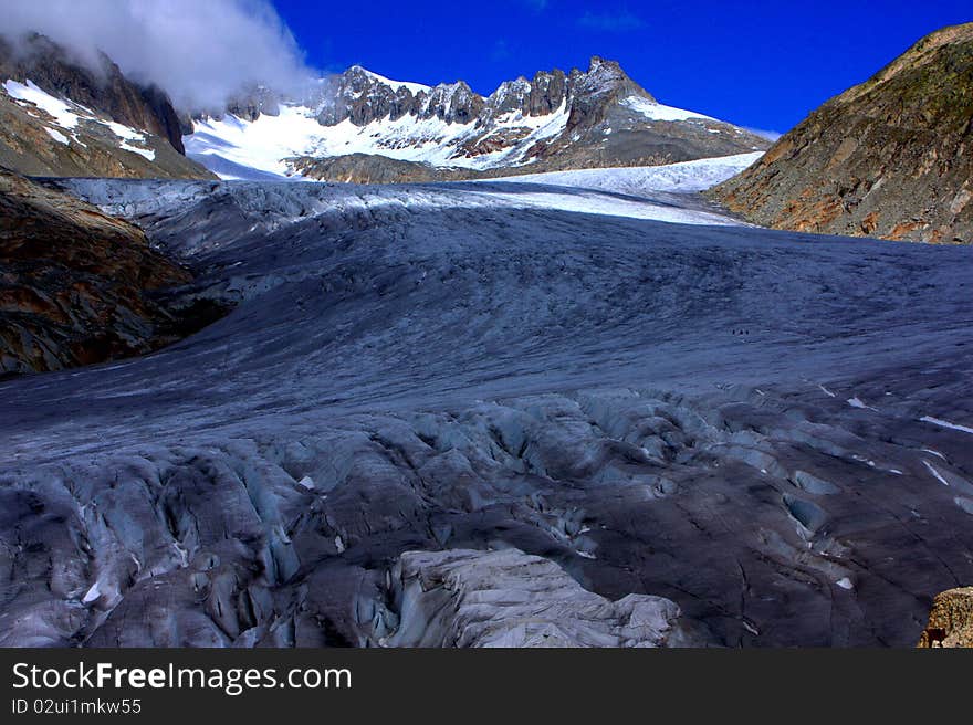 Clouds rolling into snowy mountains with a glacier