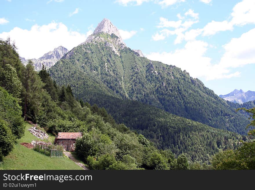 Mountain horizontal landscape with a small wooden house in northern Italy in summer. Mountain horizontal landscape with a small wooden house in northern Italy in summer