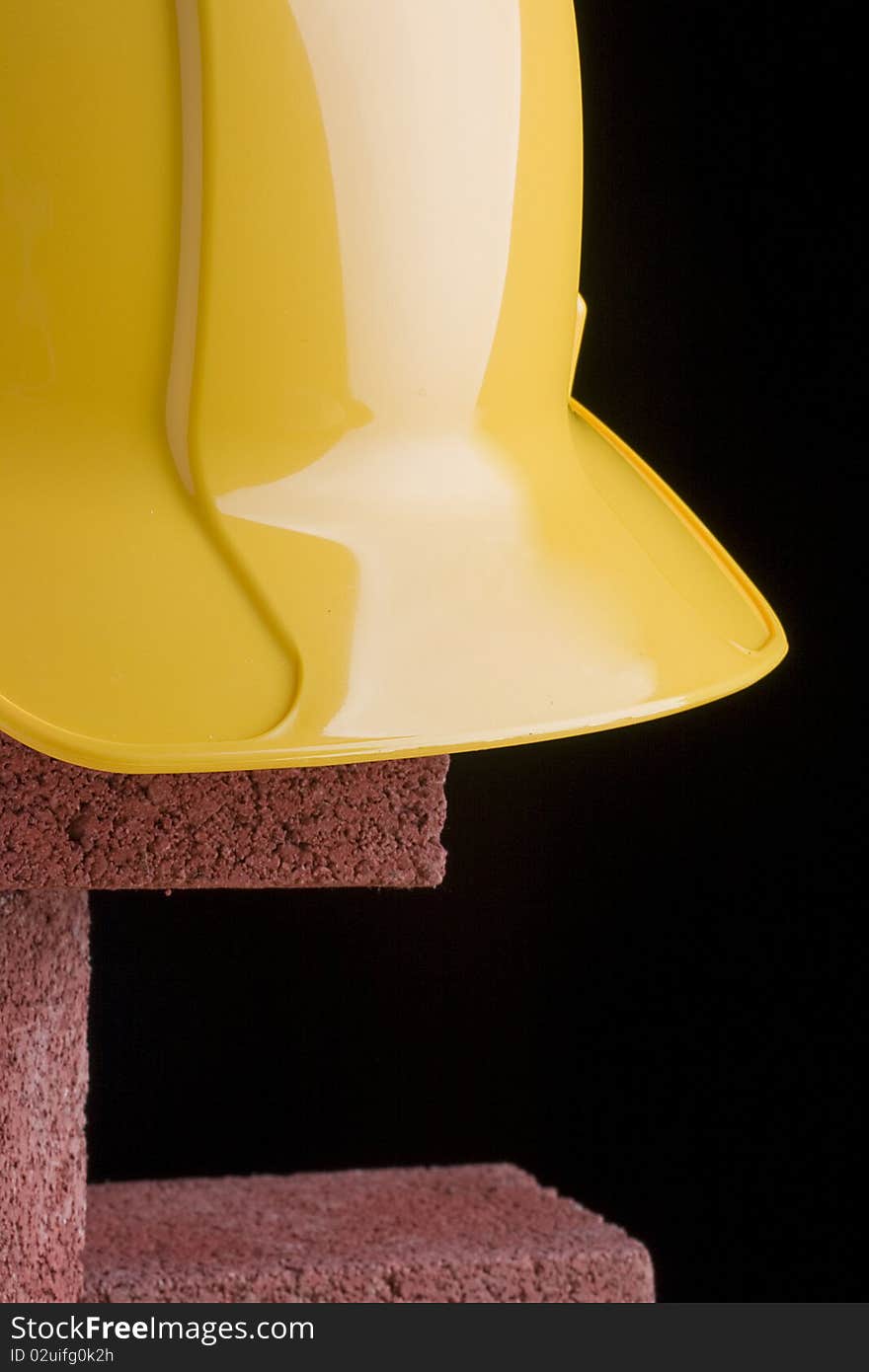 Yellow hard hat and red bricks on a black background.