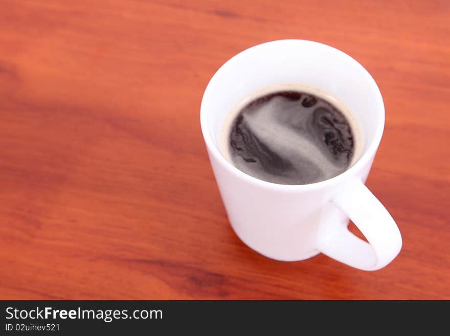 White cup with coffee on wooden desk. White cup with coffee on wooden desk