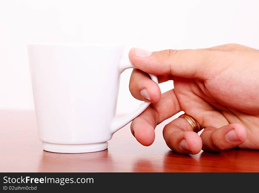 Hand taking white coffee cup. Wooden surface