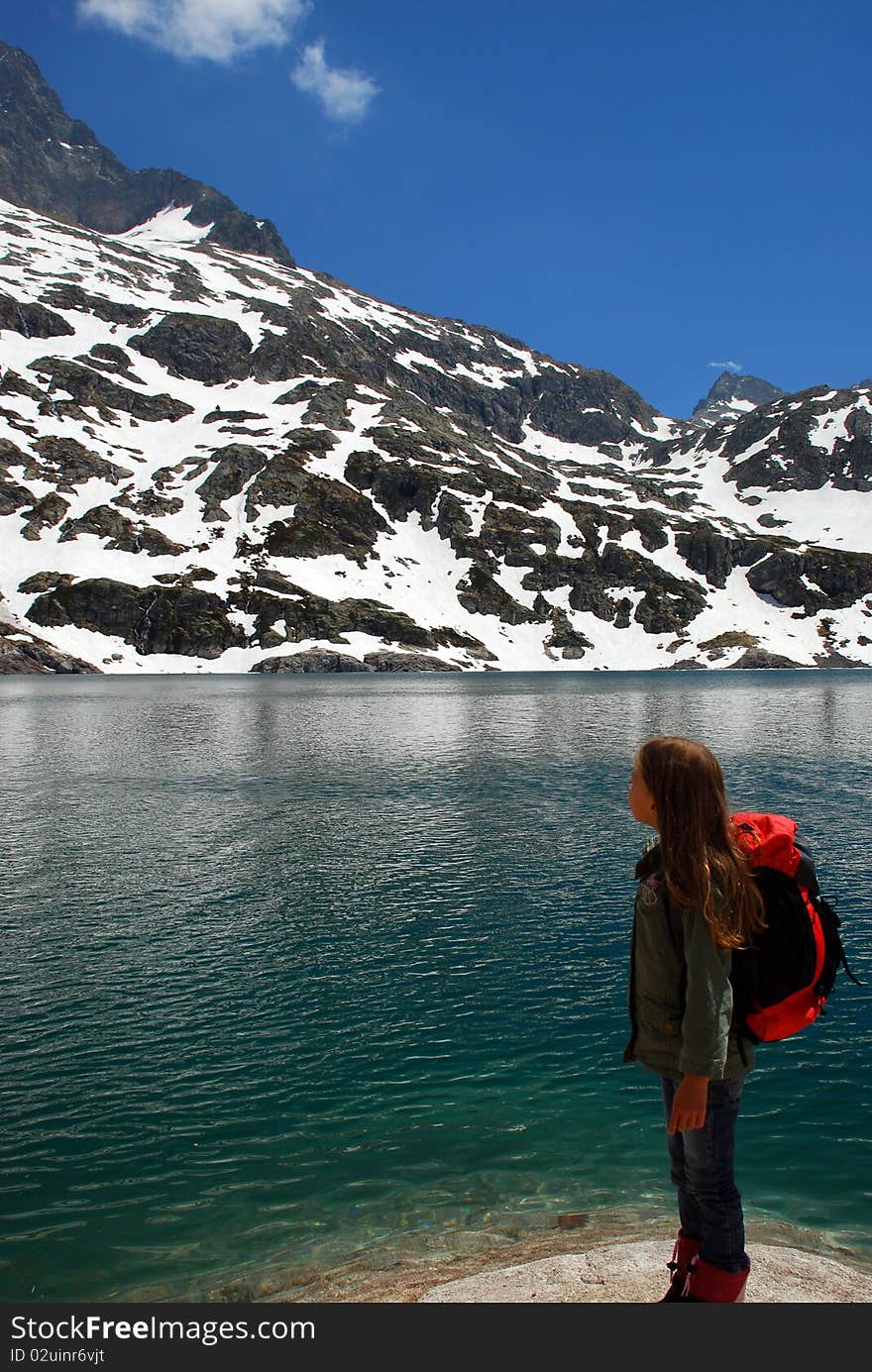 Little girl tourist in Hight mountain lake looking at beautiful landscape of Artouste lake in spring time