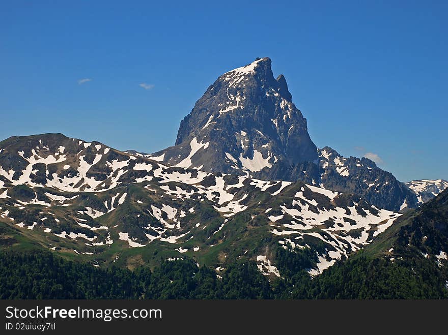 Pic Du Midi D'Ossau, 2885 m, the most beutiful mountain of Atlantic Pirenees, in Mai the snow is still in tom and green colours gain from bottom, in left from the pic is Cirque d'Aneou,. Pic Du Midi D'Ossau, 2885 m, the most beutiful mountain of Atlantic Pirenees, in Mai the snow is still in tom and green colours gain from bottom, in left from the pic is Cirque d'Aneou,