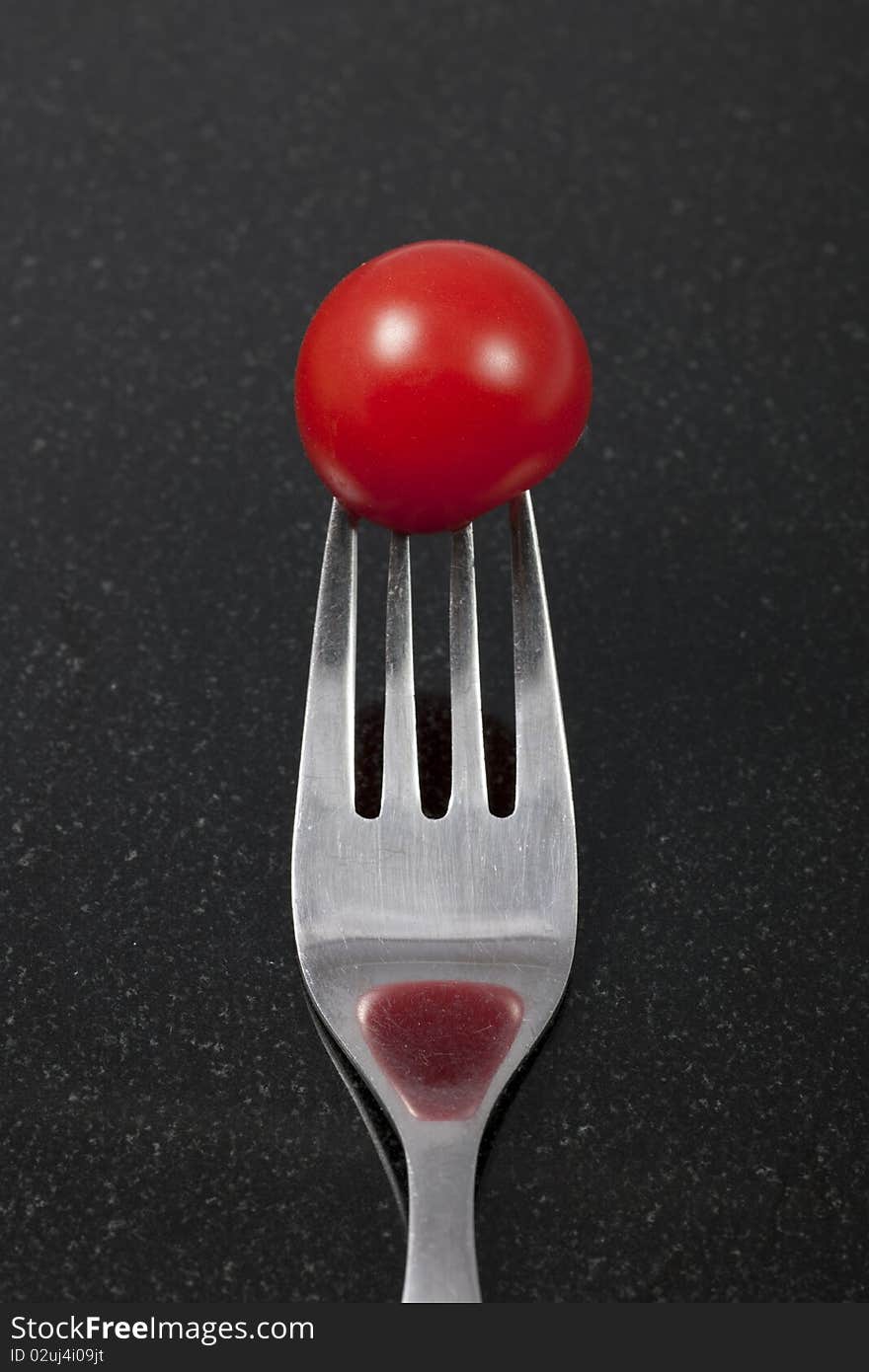 Tomato on a fork with reflection. On a black granite counter.

Note: Differential focus.