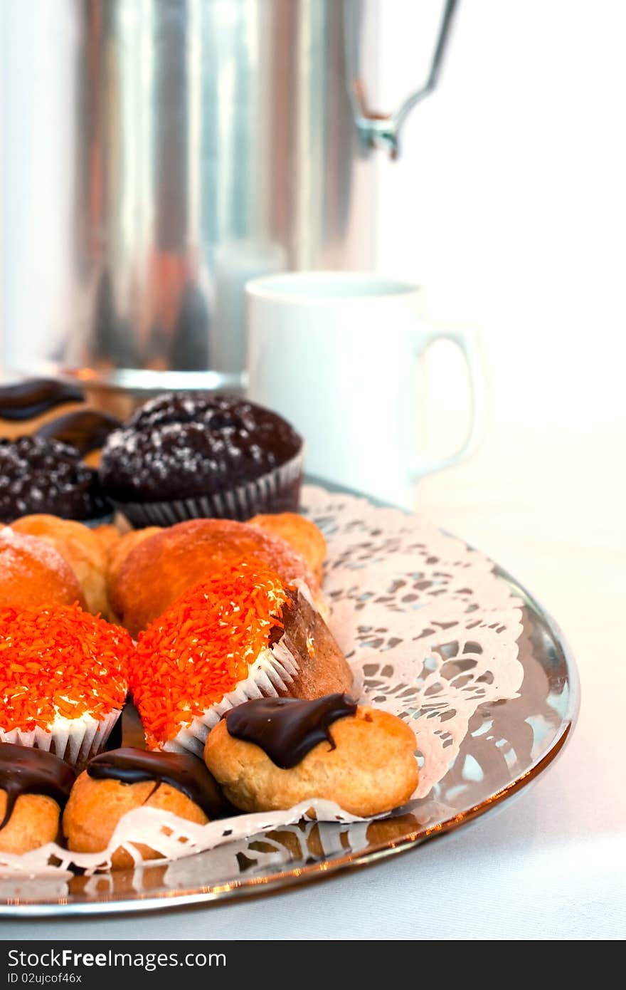 Small cakes on a plate with a coffee pot and cup in the background