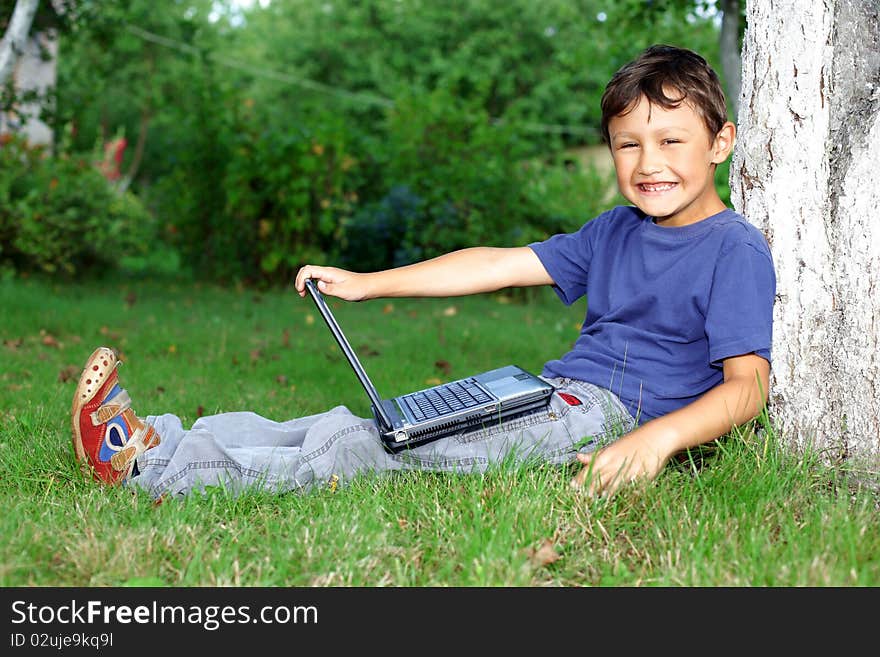 Boy with notebook sit at tree outdoors