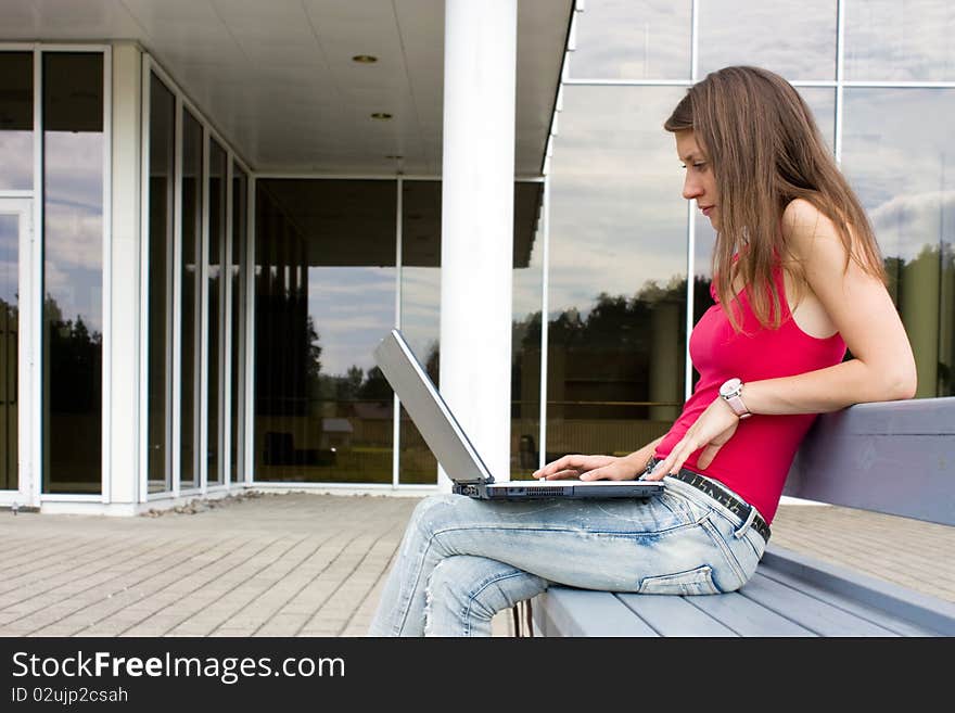 Young brunette on a bench with laptop