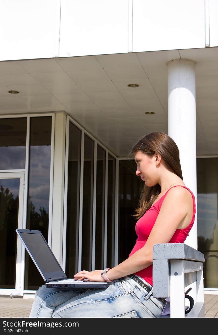 Young pretty woman with laptop sitting on the bench in a park. Young pretty woman with laptop sitting on the bench in a park