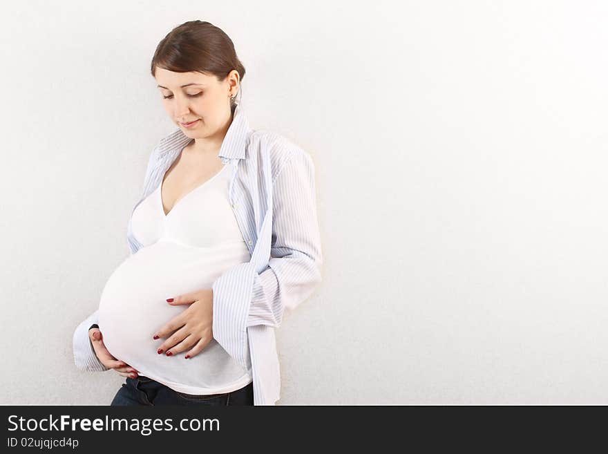 Happy pregnant woman in white near the wall