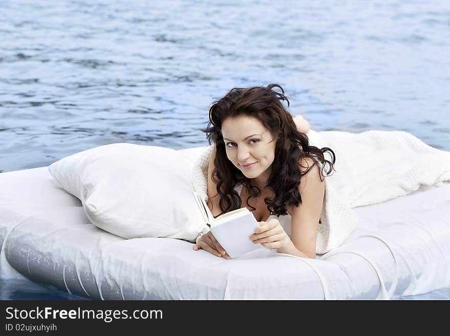 Beautiful young woman lying on the white bed in the sea. Beautiful young woman lying on the white bed in the sea