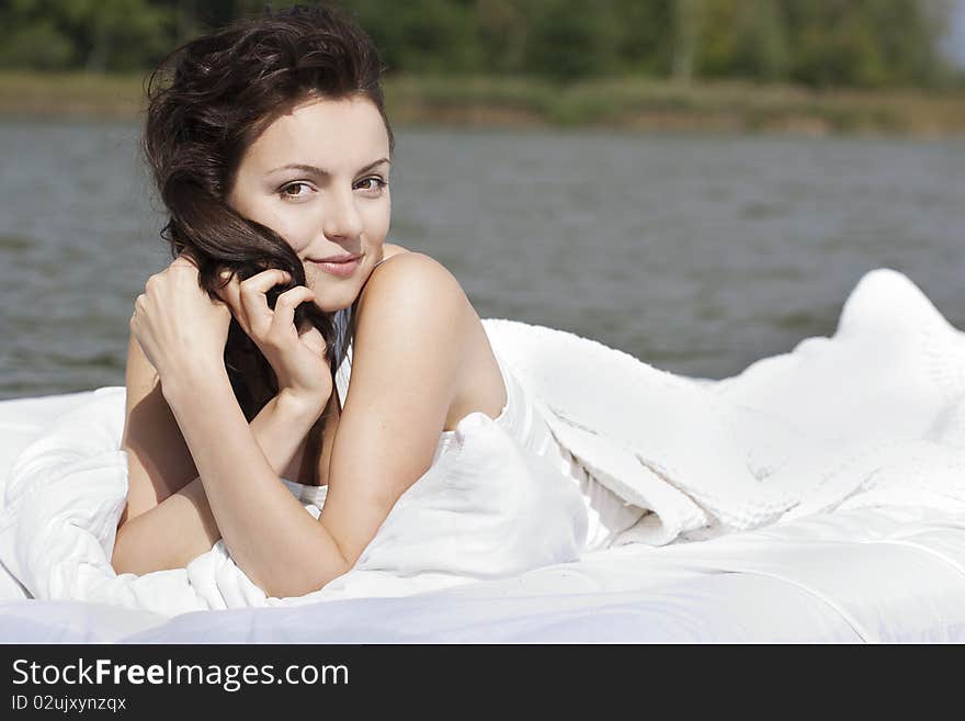 Beautiful young woman lying on the white bed in the sea. Beautiful young woman lying on the white bed in the sea