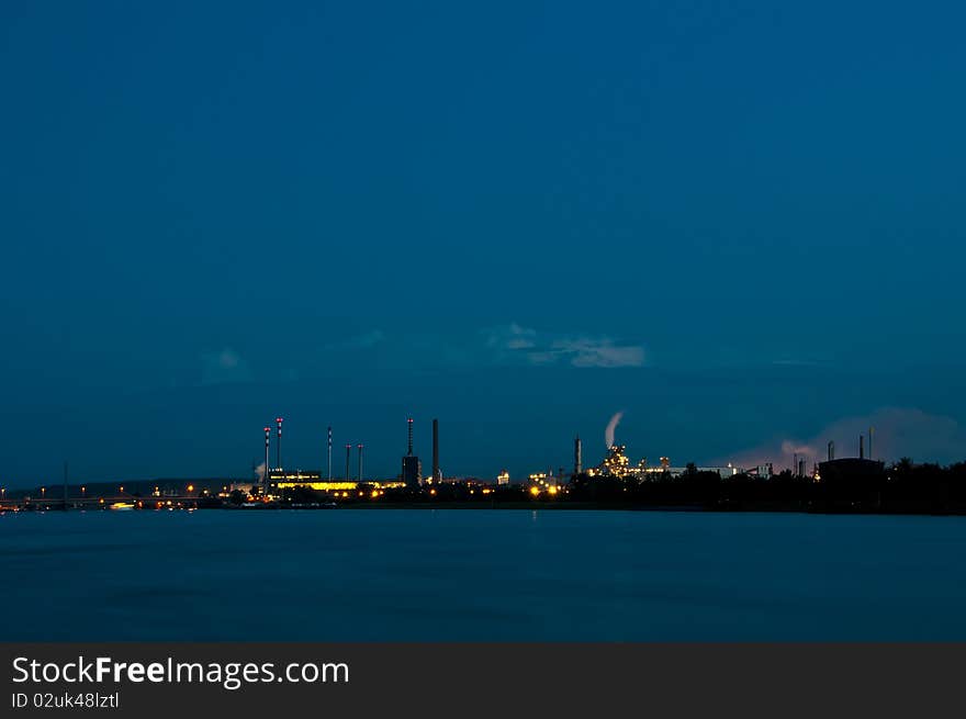 Industrial buildings in the evening. twilight. foreground is a river. background the sky. Industrial buildings in the evening. twilight. foreground is a river. background the sky