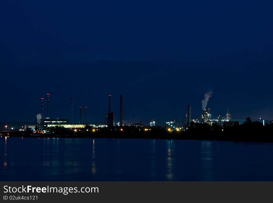 Industrial buildings in the evening. twilight. foreground is a river. background the sky. Industrial buildings in the evening. twilight. foreground is a river. background the sky