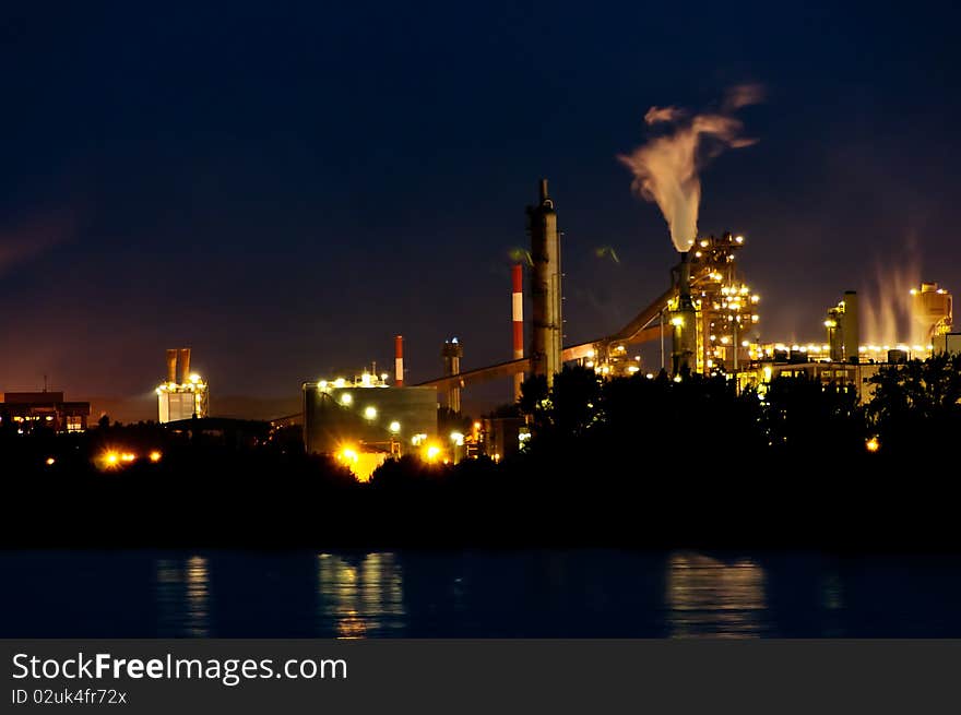 Industrial buildings in the evening. twilight. foreground is a river. background the sky. Industrial buildings in the evening. twilight. foreground is a river. background the sky