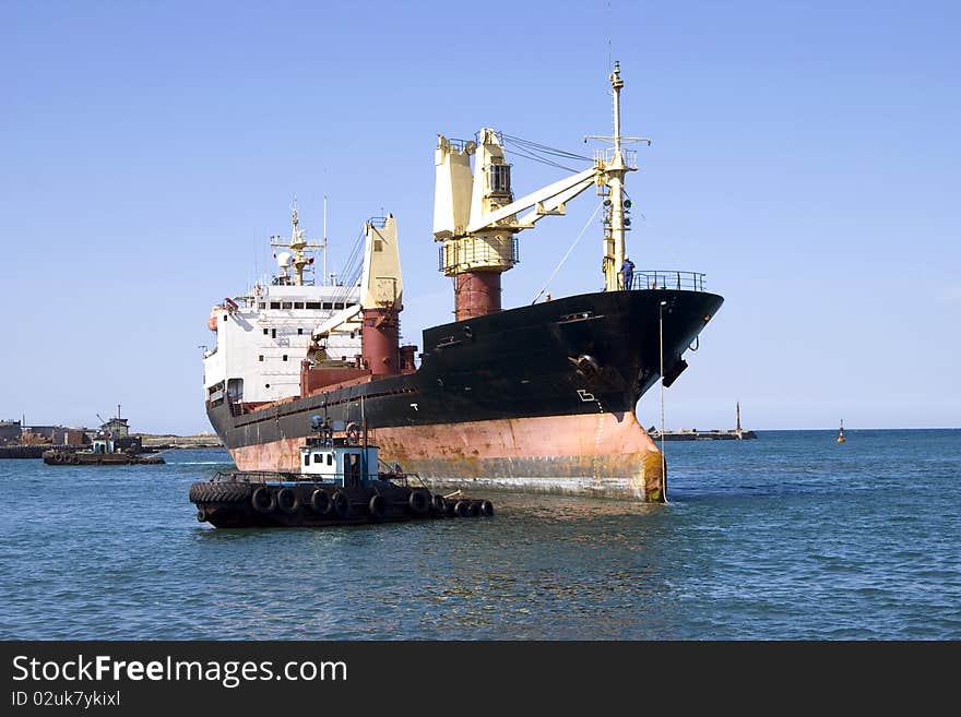 Dry-cargo ship and motorboat in seaport water area. Dry-cargo ship and motorboat in seaport water area