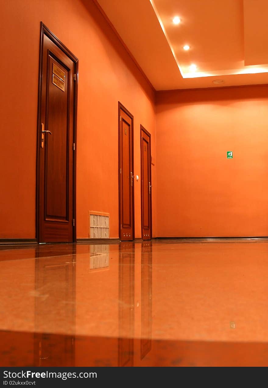 Three doors in an empty corridor, walls and a ceiling of orange color