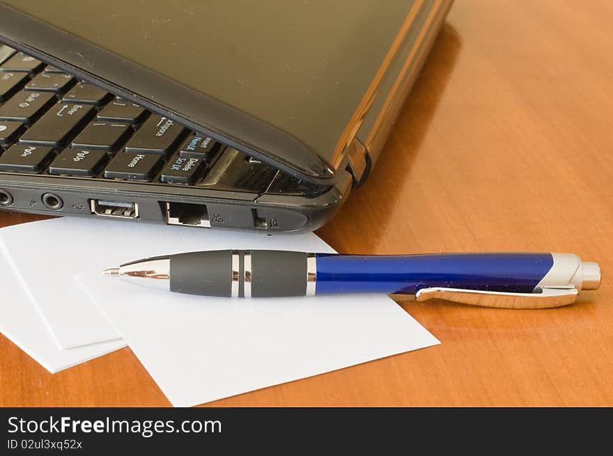 Half-opened notebook computer and pen on the writing desk. Half-opened notebook computer and pen on the writing desk