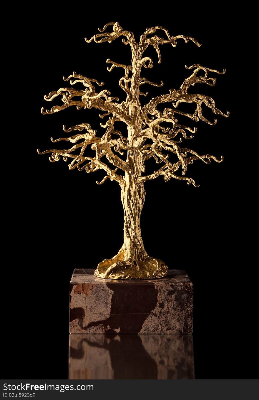 A sculpture of a golden tree. Pure gold miniature for tree on stone pedestal. A sculpture of a golden tree. Pure gold miniature for tree on stone pedestal.