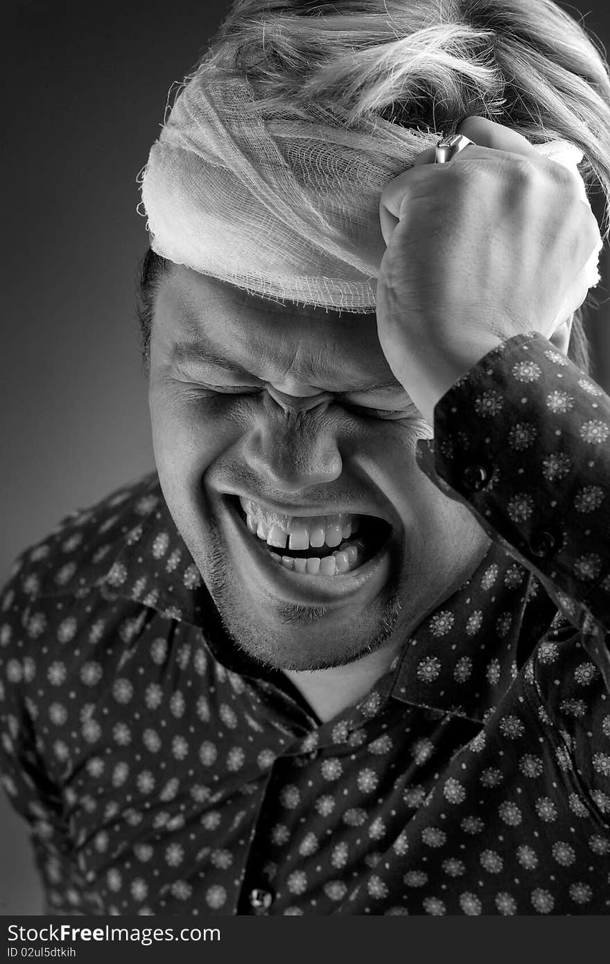 Black and white portrait of man with bandage around forehead grimacing with pain. Black and white portrait of man with bandage around forehead grimacing with pain