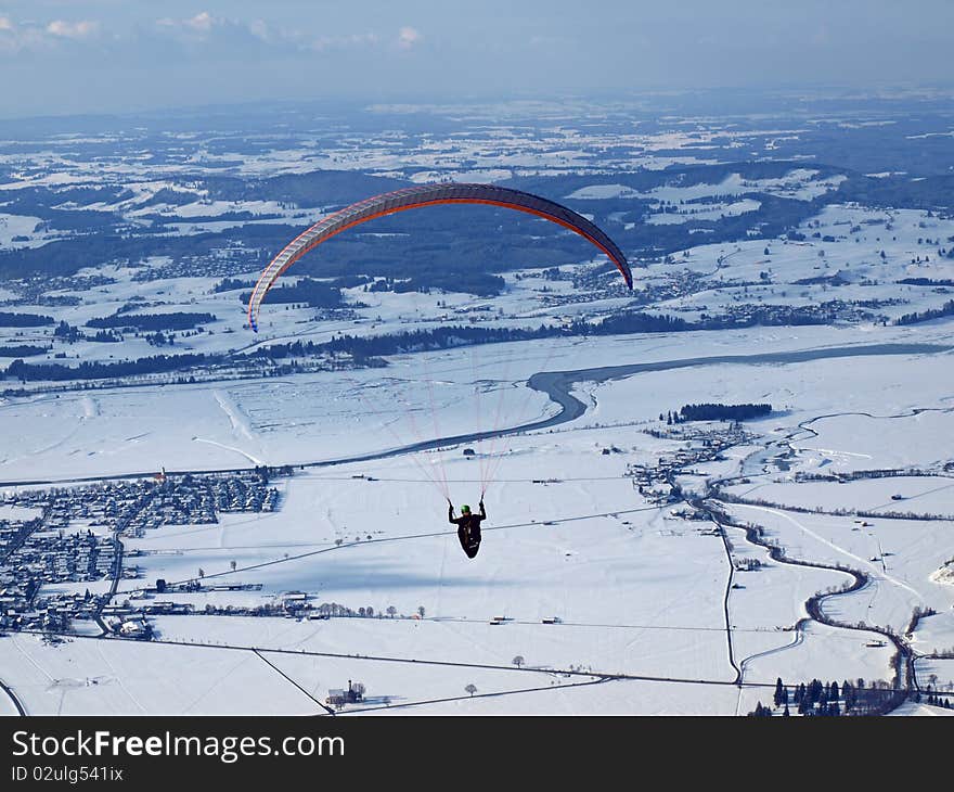 Alps close to the castle neuschwanstein in germany on a beautiful sunny winterday and a paraglider flying over the valley. Alps close to the castle neuschwanstein in germany on a beautiful sunny winterday and a paraglider flying over the valley