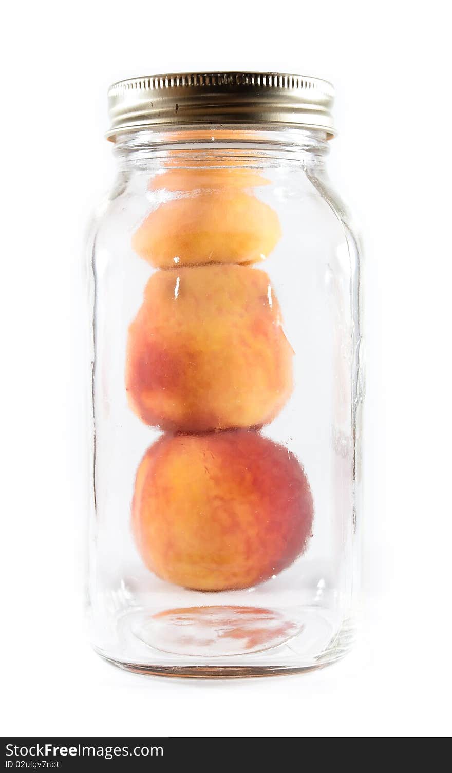 Three peaches pilled beside a glass preservative jar on a white isolated background. Three peaches pilled beside a glass preservative jar on a white isolated background.