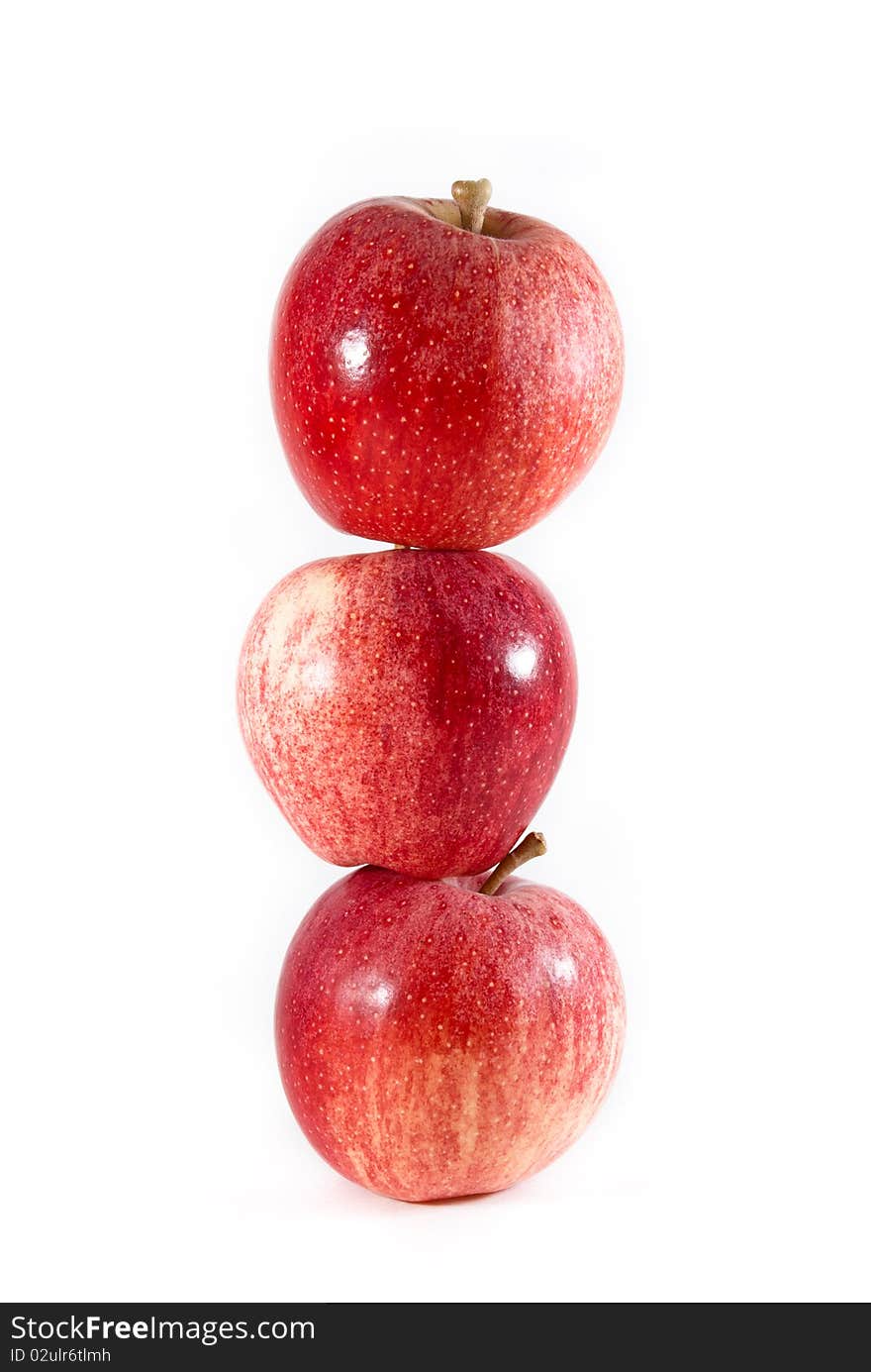 Three red and yellow gala apples balanced tall on each other on a white isolated background. Three red and yellow gala apples balanced tall on each other on a white isolated background.