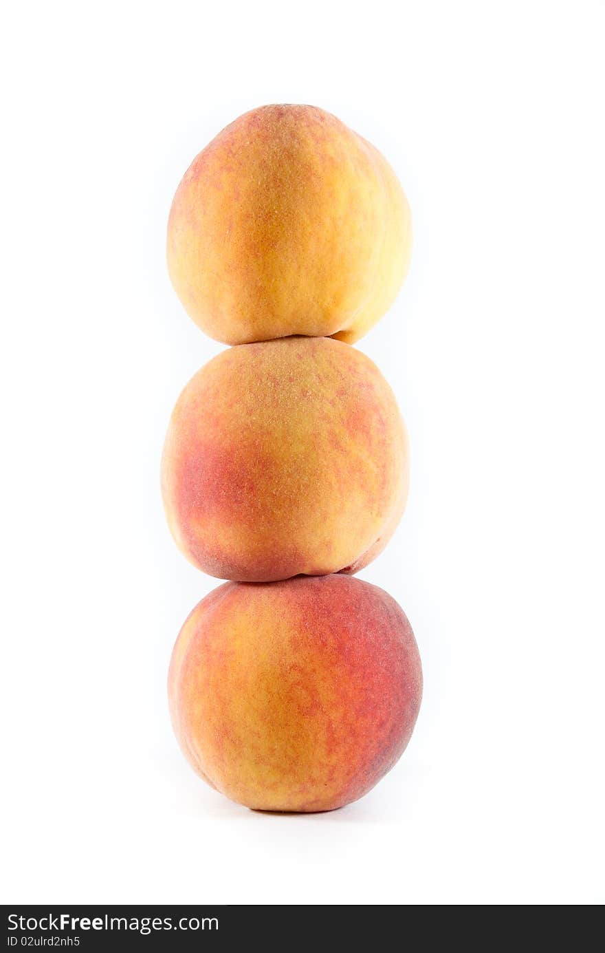 Three fresh fuzzy yellow and orange peaches stacked on each other on a white isolated background. Three fresh fuzzy yellow and orange peaches stacked on each other on a white isolated background.