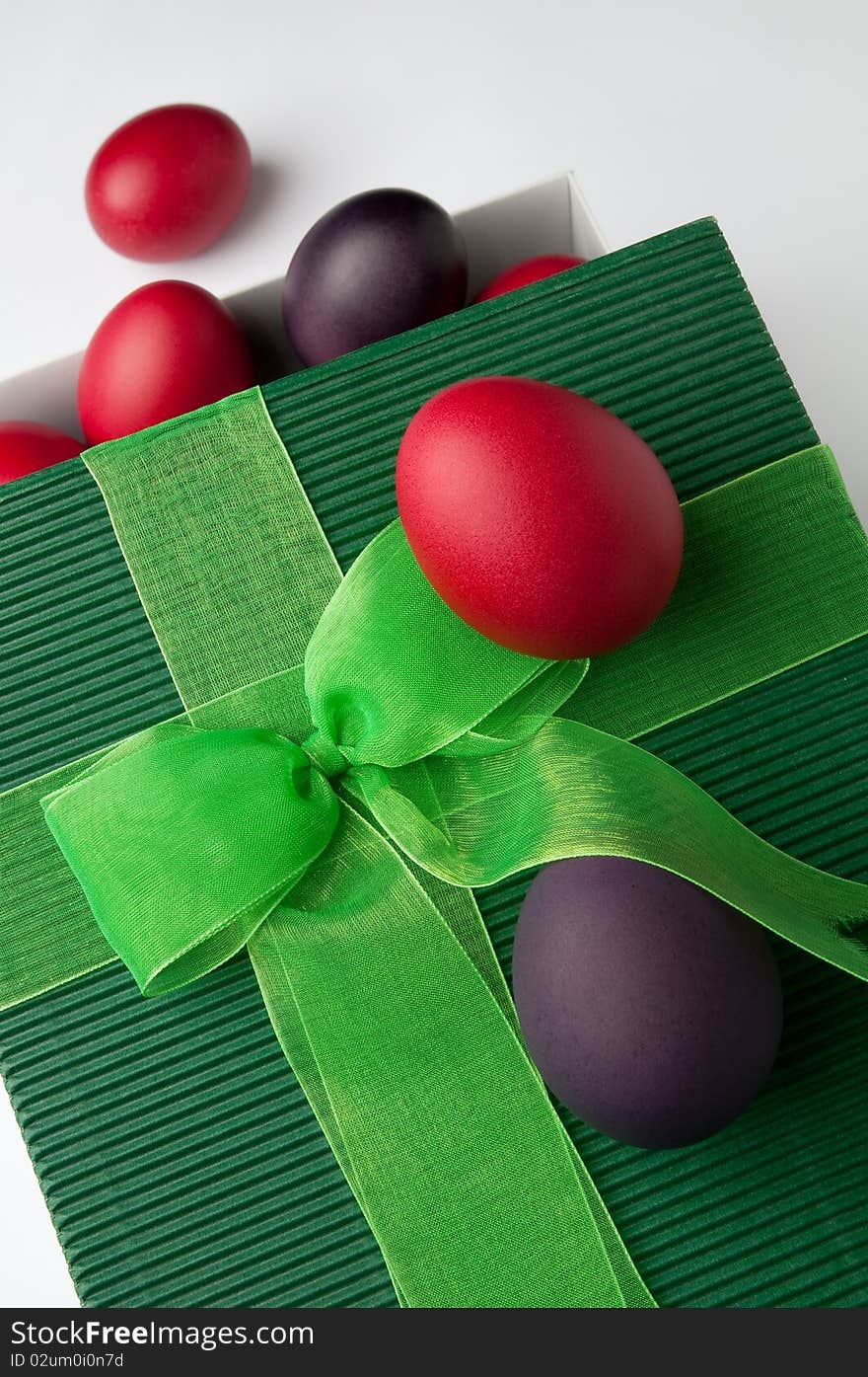 Many Easter eggs of different colours and a green gift box.