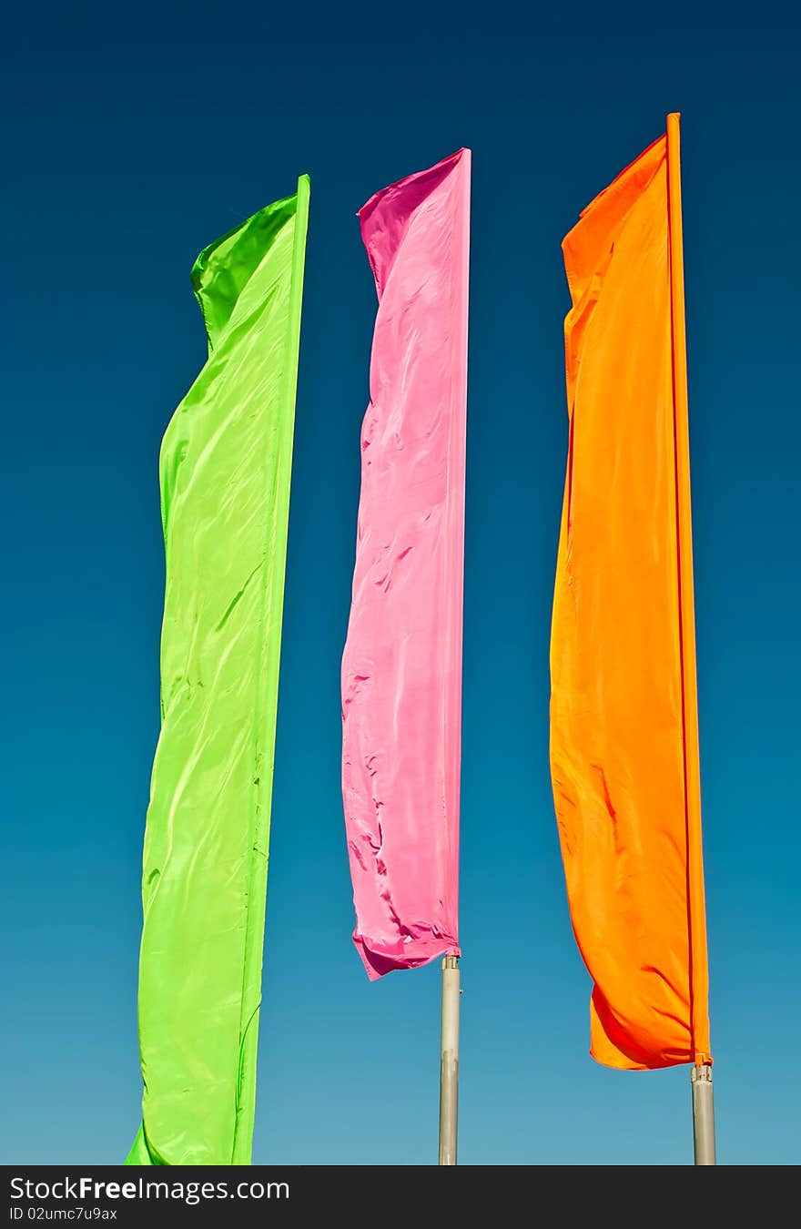 Flags - green, pink, orange against the blue sky