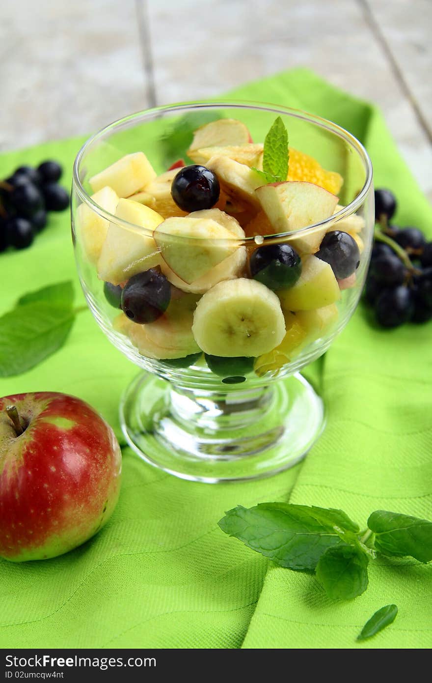 Fruit salad in a glass bowl on a green cloth