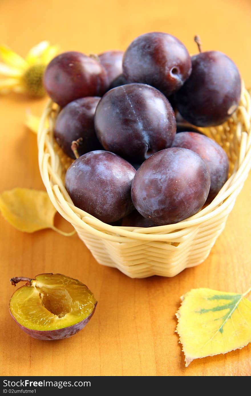 Plums in a basket with a blue cloth