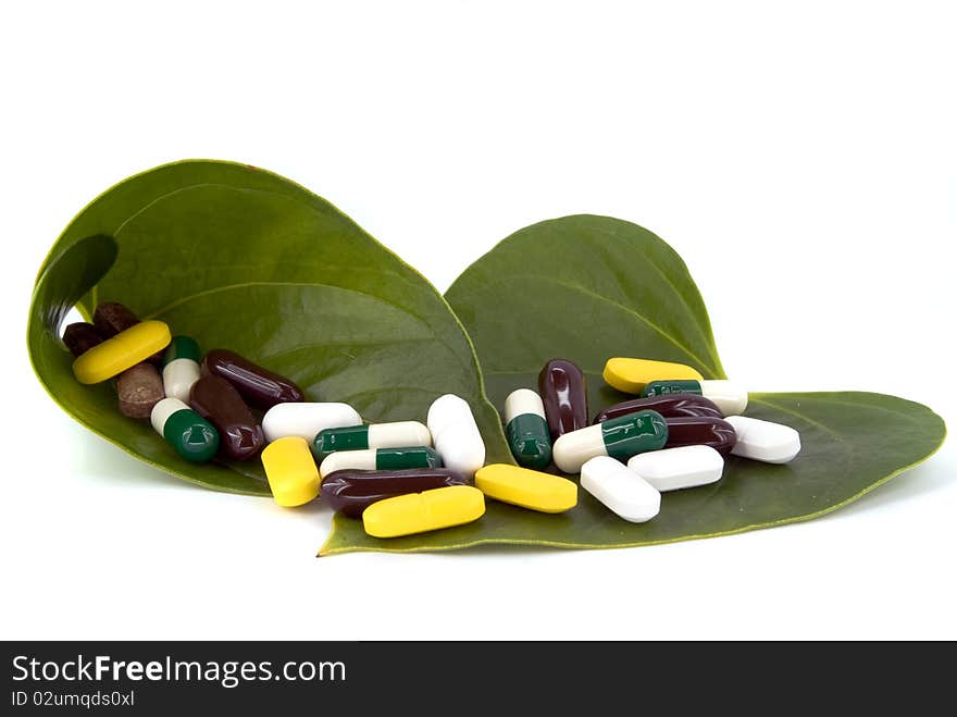 Pills in green leaf on white background