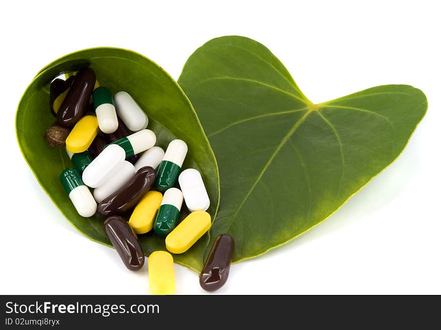 Pills in green leaf on white background