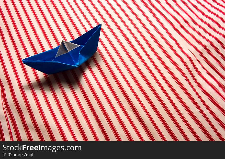 Blue paper boat on striped material