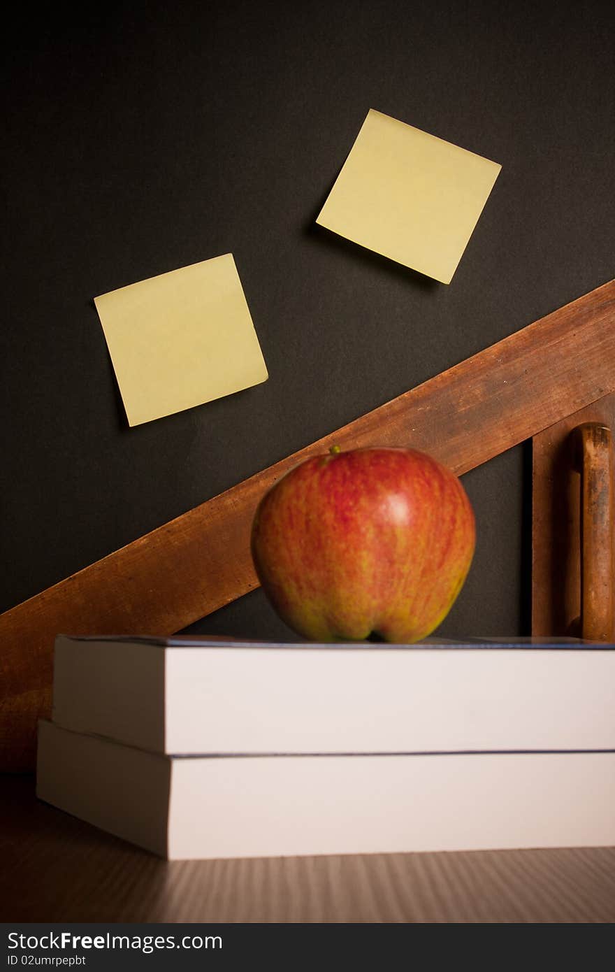 School books with apple on desk and notes on board. School books with apple on desk and notes on board