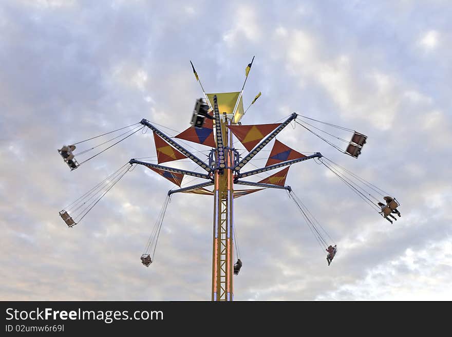 A tower county fair swing ride against a colorful evening sky, the motion creating a slight blur to the passengers. A tower county fair swing ride against a colorful evening sky, the motion creating a slight blur to the passengers