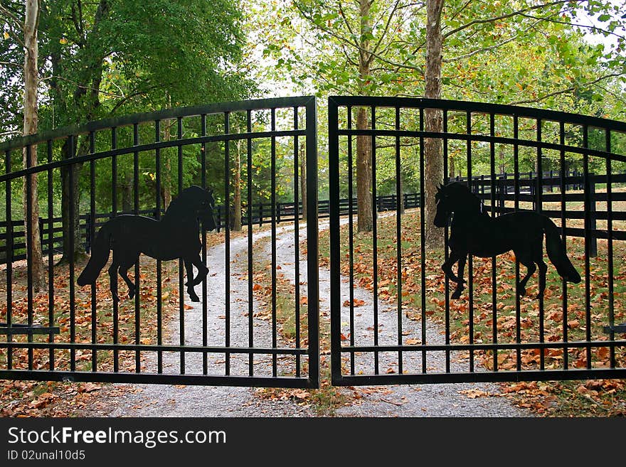 Closed iron gates with silhouettes of horses, barring entrance to a ranch. Closed iron gates with silhouettes of horses, barring entrance to a ranch