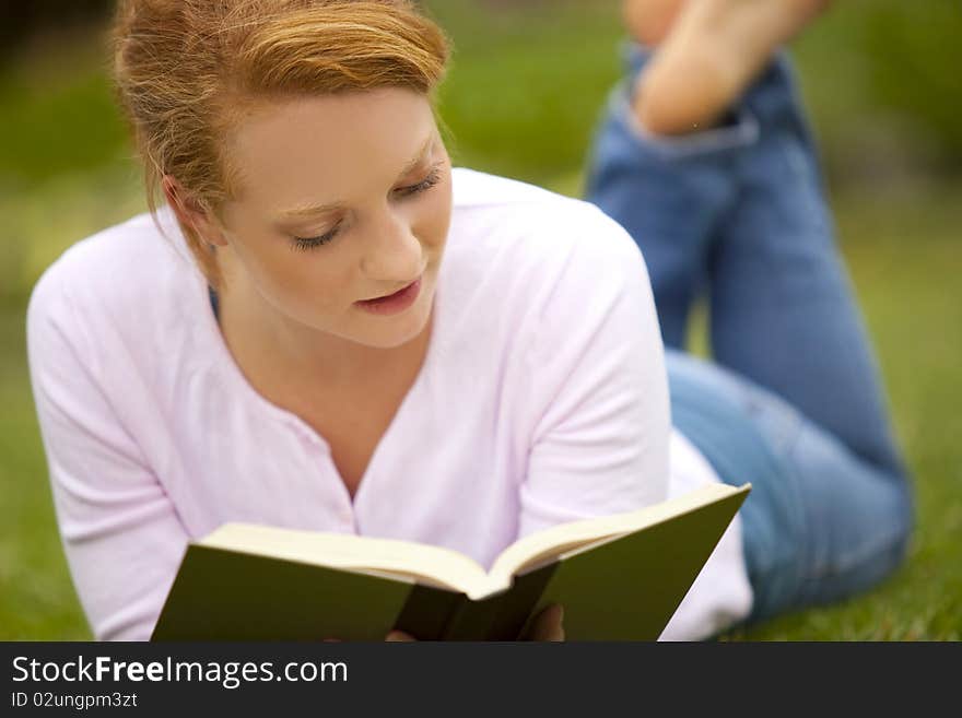 Young woman sitting outside reading. Young woman sitting outside reading