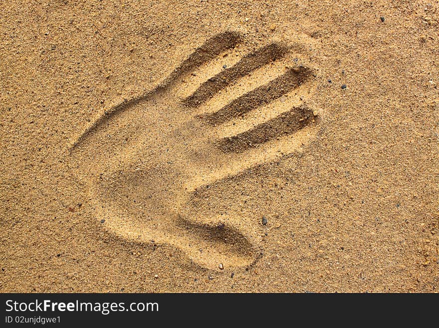 Print of a human hand on sand