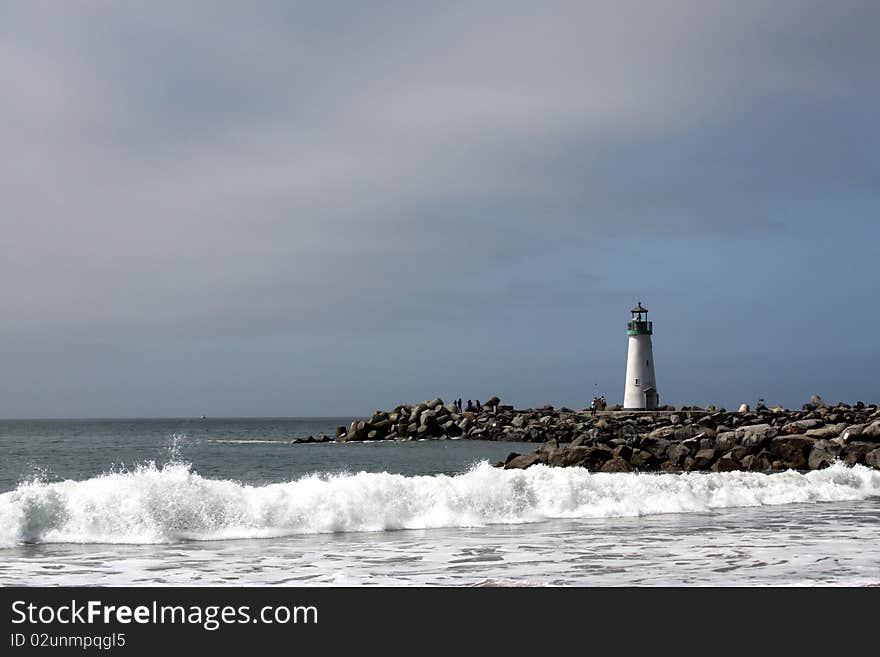 Lighthouse and sea waves crashing on rocks