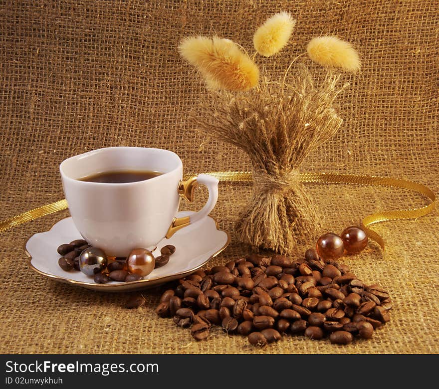 Coffee cup and coffee beans over burlap background