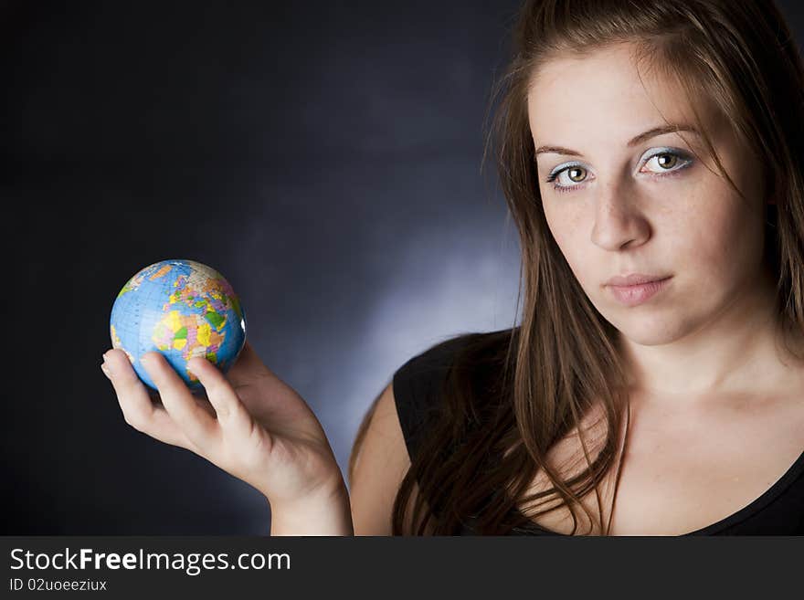 Portrait of a beautiful blond girl holding a globe in one hand isolated on black with white. Portrait of a beautiful blond girl holding a globe in one hand isolated on black with white