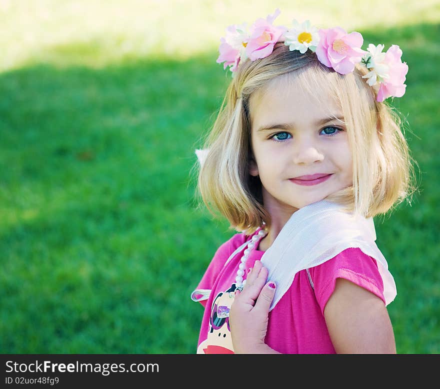 Smiling little girl playing dress up with fairy wings and pearls.