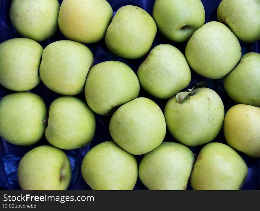 A texture or pattern of green apples stacked together. A texture or pattern of green apples stacked together