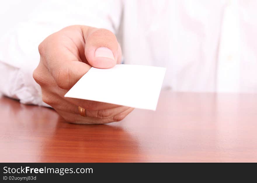 Hand giving a blank business card on wooden desk