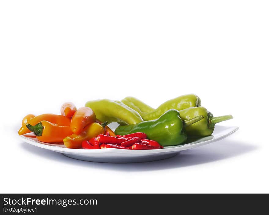 Red, orange and green chili peppers from Thailand on a white plate. Isolated on white. Red, orange and green chili peppers from Thailand on a white plate. Isolated on white.