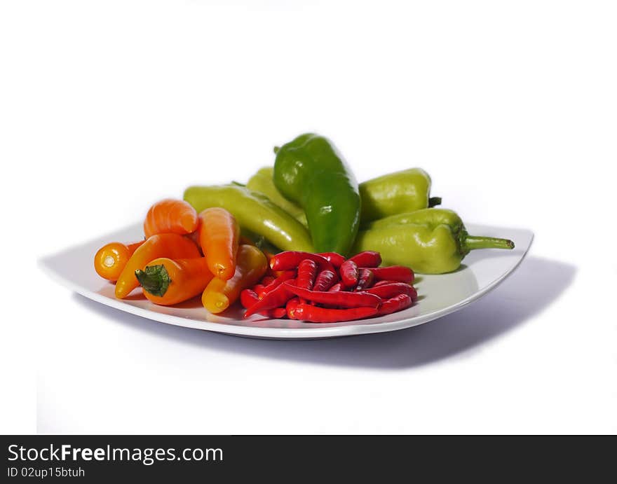 Assorted chili peppers on a white plate, isolated