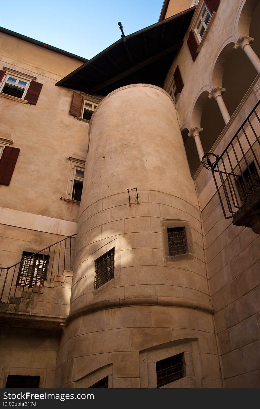 Courtyard of Castel Thun windows with rocks and a pit on the floor