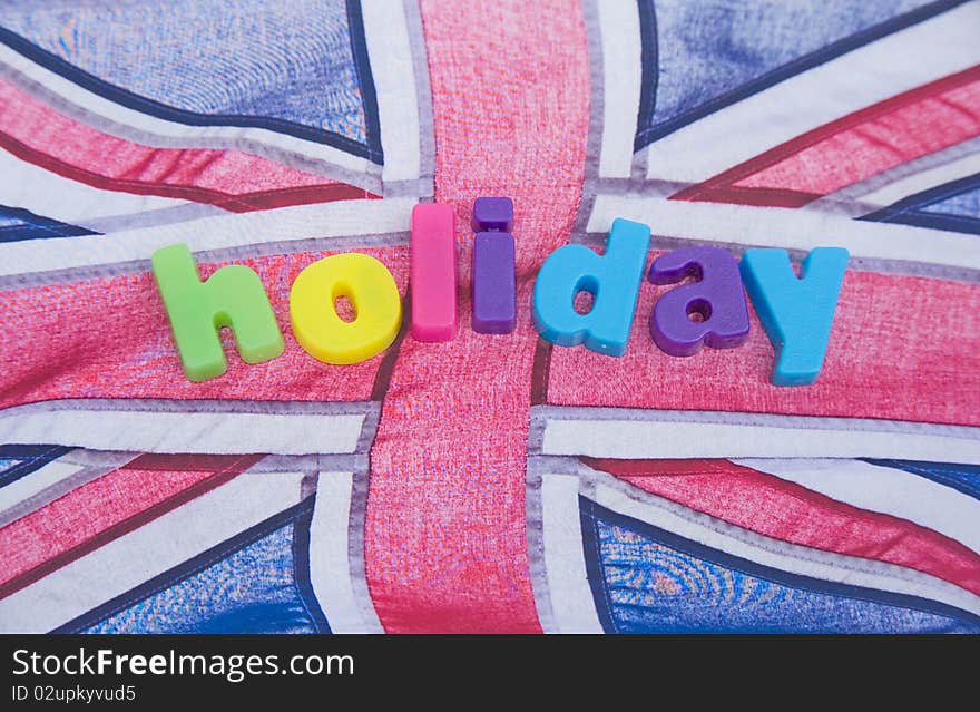 An image of the word holiday in colorful lower case letters placed on a blowing Union Jack flag. An image of the word holiday in colorful lower case letters placed on a blowing Union Jack flag.